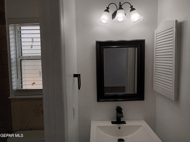 bathroom with an inviting chandelier and a sink