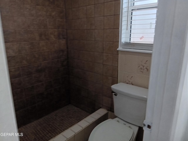 full bathroom featuring toilet and a tile shower
