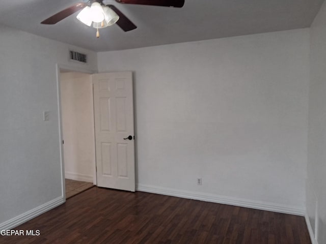 spare room featuring dark wood-style floors, baseboards, ceiling fan, and visible vents