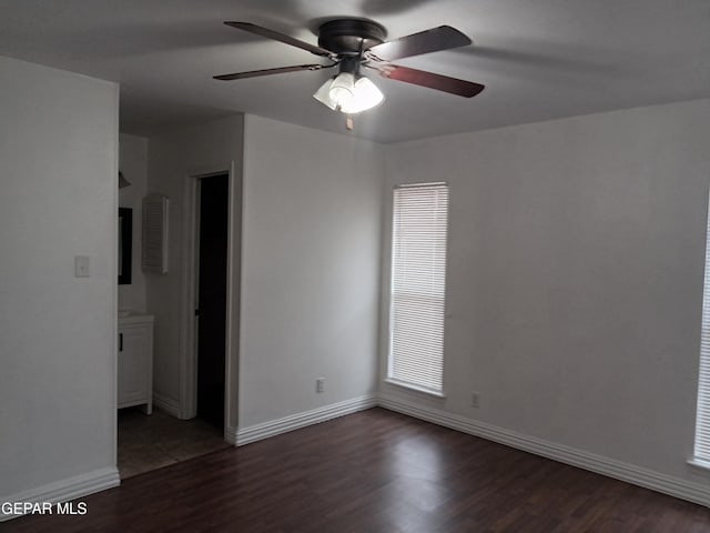 spare room featuring baseboards, wood finished floors, and a ceiling fan