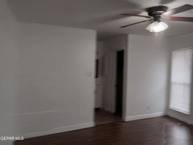 unfurnished room featuring dark wood-type flooring, baseboards, and a ceiling fan