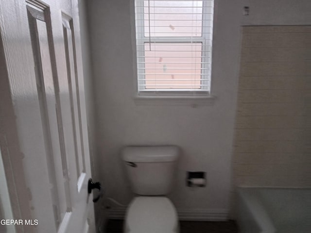 bathroom with toilet and a washtub