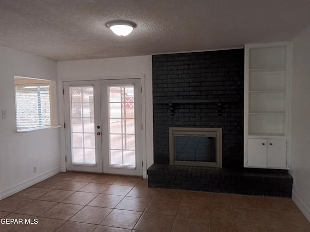 unfurnished living room with light tile patterned flooring, a wealth of natural light, french doors, and a textured ceiling