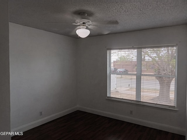 empty room featuring a textured ceiling, baseboards, ceiling fan, and dark wood finished floors