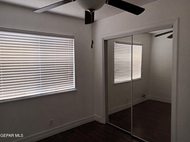 unfurnished bedroom with a closet, baseboards, wood finished floors, and a ceiling fan