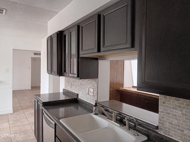 kitchen with light tile patterned flooring, visible vents, dishwasher, dark countertops, and a sink