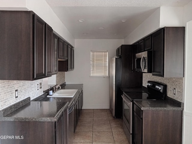 kitchen with a sink, dark countertops, dark brown cabinets, and appliances with stainless steel finishes