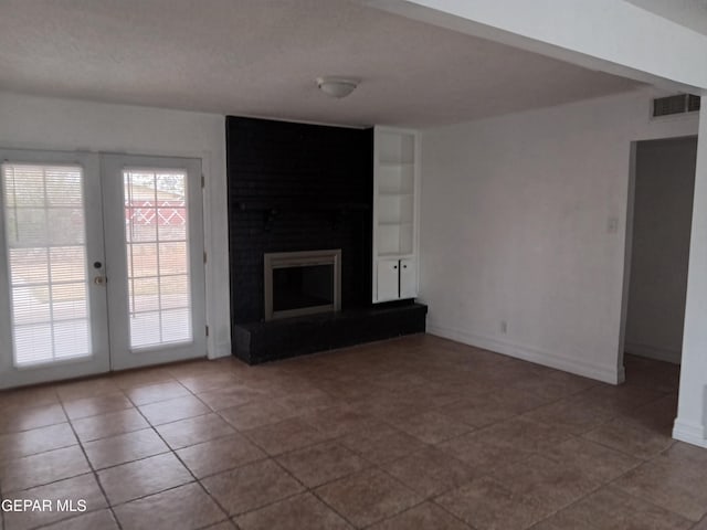 unfurnished living room with a large fireplace, visible vents, baseboards, french doors, and tile patterned flooring