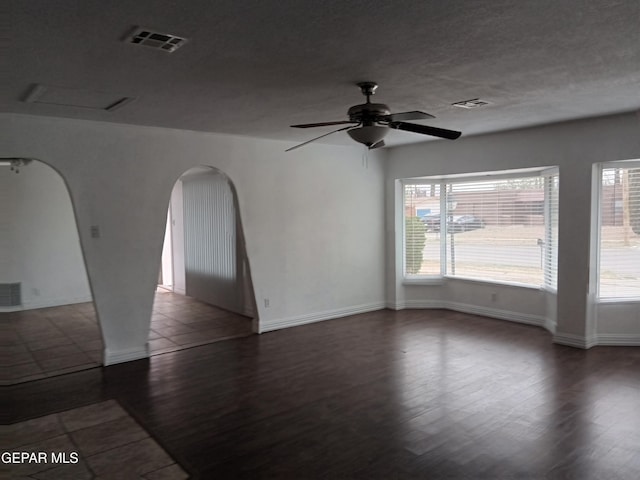 unfurnished room featuring visible vents, wood finished floors, and arched walkways