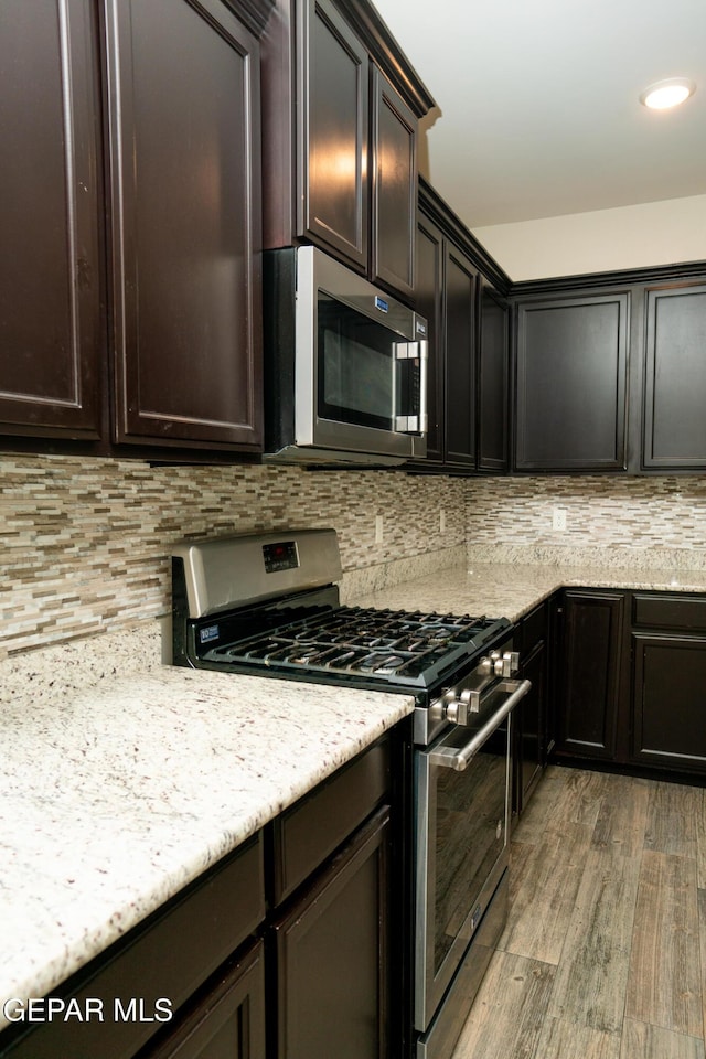 756 Jalynn Grace, Canutillo, TX 79835 - kitchen featuring stainless steel appliances, light wood finished floors, decorative backsplash, dark brown cabinets, and light stone countertops