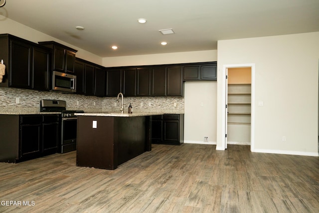 756 Jalynn Grace, Canutillo, TX 79835 - kitchen featuring appliances with stainless steel finishes, dark wood-style flooring, tasteful backsplash, an island with sink, and light stone countertops