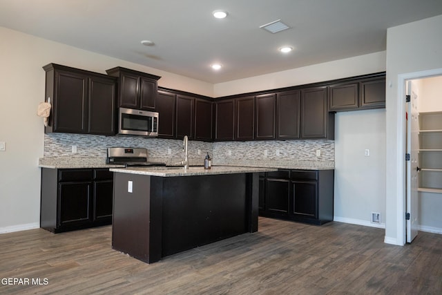 756 Jalynn Grace, Canutillo, TX 79835 - kitchen featuring appliances with stainless steel finishes, dark wood-style floors, decorative backsplash, light stone countertops, and a kitchen island with sink