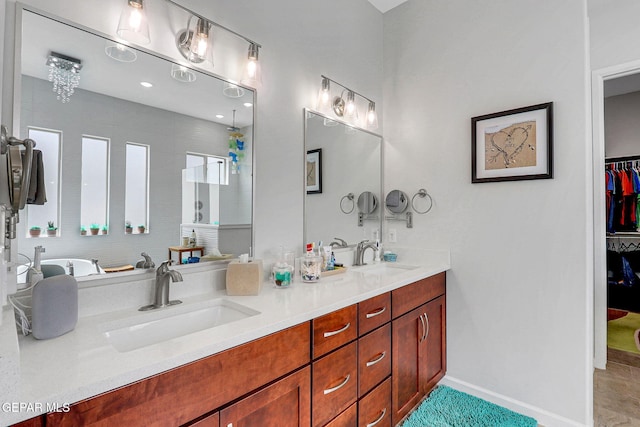 full bathroom with a walk in closet, baseboards, a sink, and double vanity