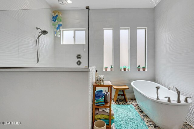 bathroom with a soaking tub, tile walls, and a tile shower