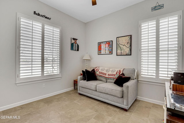 sitting room with ceiling fan, baseboards, light tile patterned floors, and plenty of natural light