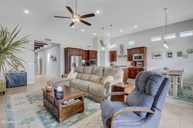 living area with visible vents, a ceiling fan, a towering ceiling, and light tile patterned flooring