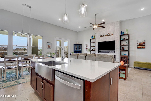 kitchen featuring stainless steel dishwasher, a sink, a ceiling fan, light countertops, and light tile patterned floors