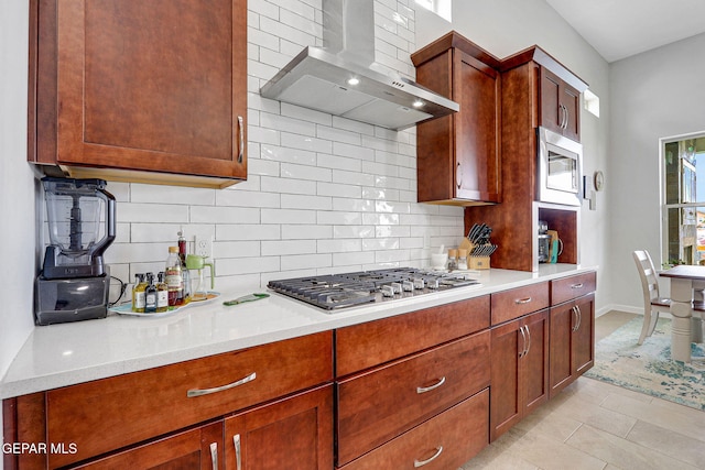 kitchen featuring wall chimney exhaust hood, stainless steel appliances, light countertops, and tasteful backsplash