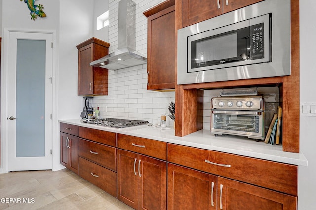 kitchen featuring tasteful backsplash, a toaster, light countertops, wall chimney exhaust hood, and appliances with stainless steel finishes