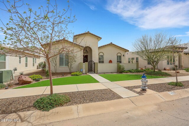 mediterranean / spanish-style home with a gate, a front yard, a tiled roof, and stucco siding