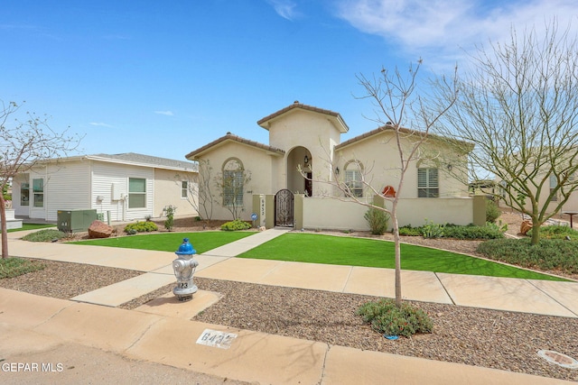 mediterranean / spanish-style house with stucco siding, a front lawn, a tiled roof, and a gate