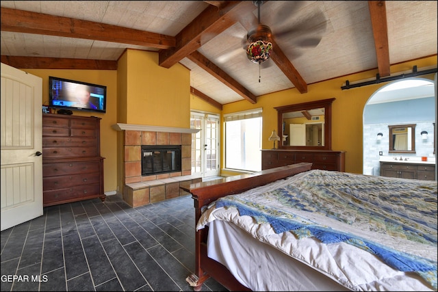 29 Cielo Vis, Anthony, NM 88021 - bedroom featuring lofted ceiling with beams, dark wood-style flooring, ensuite bathroom, a tiled fireplace, and arched walkways