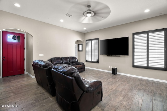 living room with arched walkways, baseboards, wood finished floors, and ceiling fan