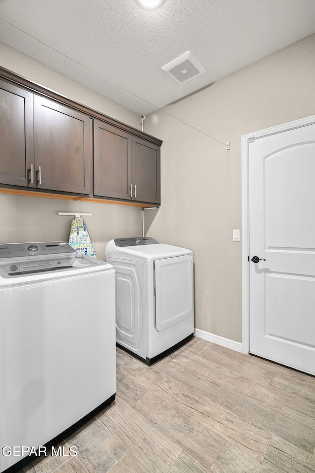 clothes washing area with a textured ceiling, light wood-style floors, visible vents, independent washer and dryer, and cabinet space
