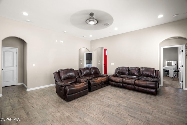 living room with arched walkways, ceiling fan, and light wood-type flooring