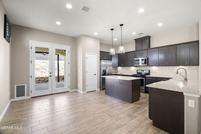 kitchen featuring light stone counters, a kitchen island, visible vents, appliances with stainless steel finishes, and a sink