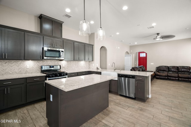kitchen with a peninsula, open floor plan, visible vents, appliances with stainless steel finishes, and arched walkways