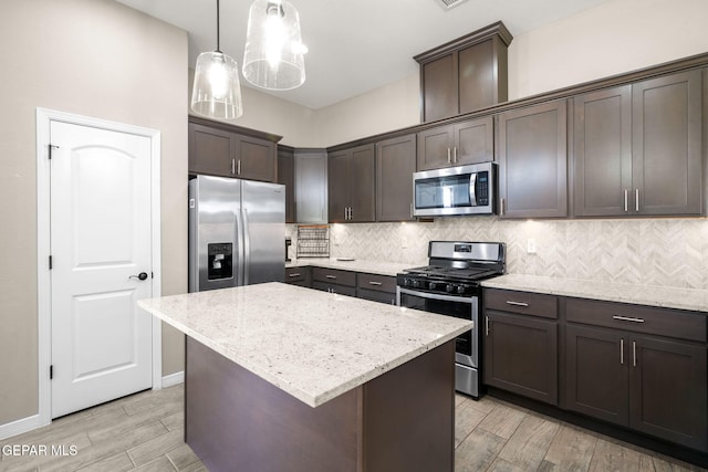 kitchen with tasteful backsplash, appliances with stainless steel finishes, dark brown cabinets, wood finish floors, and light stone countertops