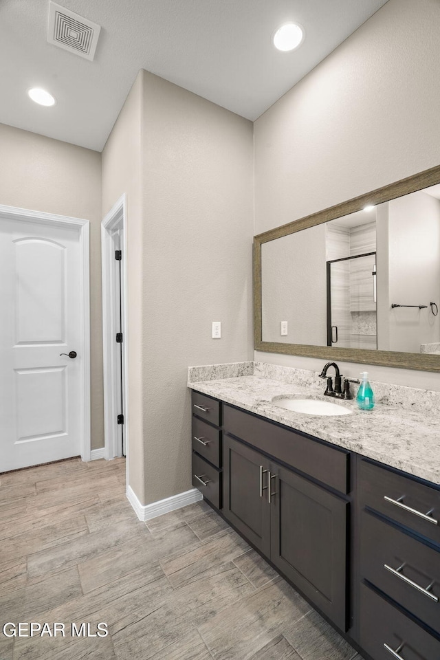 bathroom with visible vents, baseboards, vanity, wood finished floors, and a stall shower