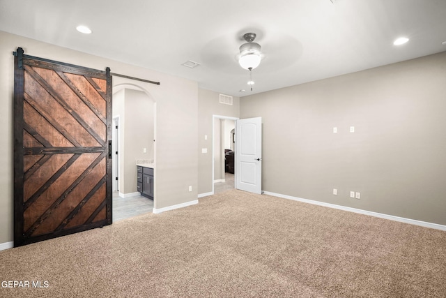 unfurnished bedroom with arched walkways, light colored carpet, baseboards, and visible vents