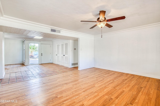 empty room featuring visible vents, baseboards, ornamental molding, a ceiling fan, and light wood-style floors