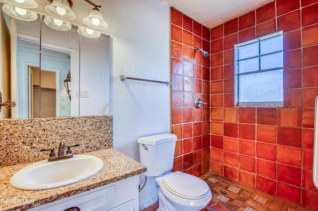 bathroom featuring tiled shower, vanity, and toilet