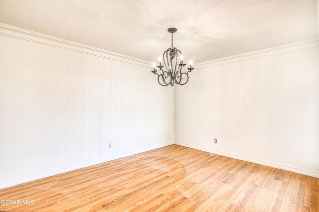 unfurnished room featuring a notable chandelier, baseboards, crown molding, and wood finished floors