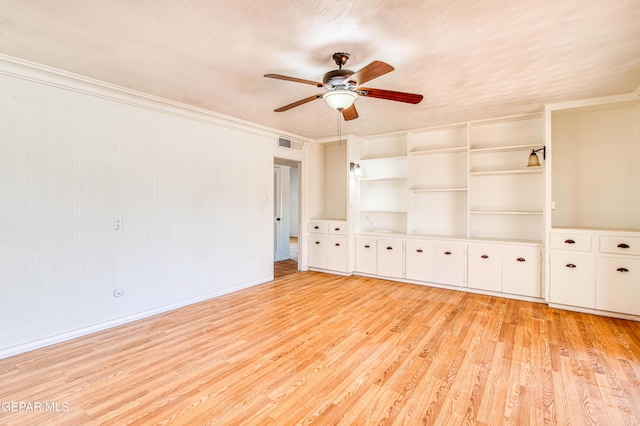 empty room featuring visible vents, baseboards, light wood-type flooring, a ceiling fan, and crown molding
