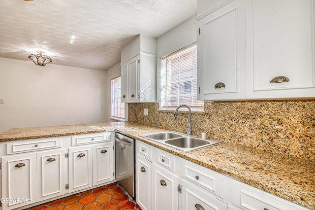 kitchen with stainless steel dishwasher, a peninsula, white cabinets, a sink, and backsplash