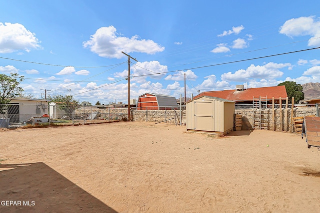 view of yard featuring an outbuilding, a storage unit, and fence