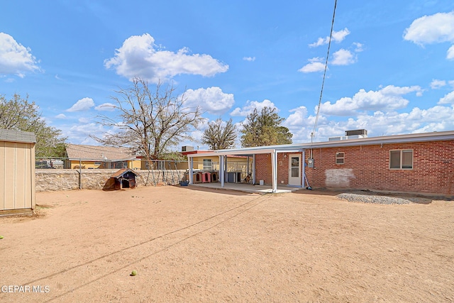 back of property with brick siding, fence, and a patio area