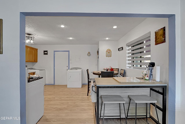 kitchen featuring a kitchen bar, washer / clothes dryer, and light wood finished floors