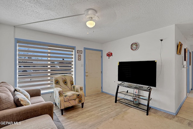 living room featuring light wood-style flooring, a textured ceiling, and ceiling fan
