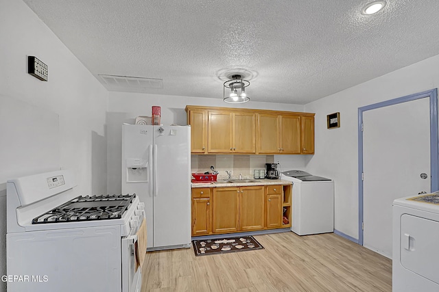 kitchen featuring white appliances, light wood-type flooring, visible vents, and washer / clothes dryer