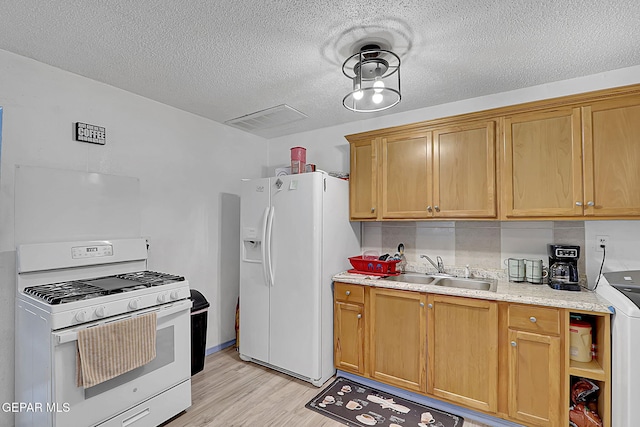 kitchen featuring white appliances, a textured ceiling, a sink, light wood-style floors, and visible vents