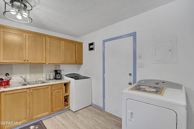 laundry area with electric panel, light wood finished floors, a sink, cabinet space, and washer and clothes dryer