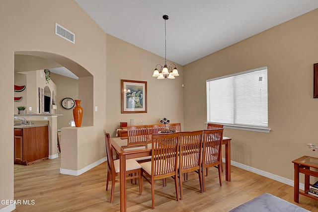 7101 Luz De Sol Dr, El Paso, TX 79912 - dining area featuring light wood-style flooring, arched walkways, vaulted ceiling, and visible vents