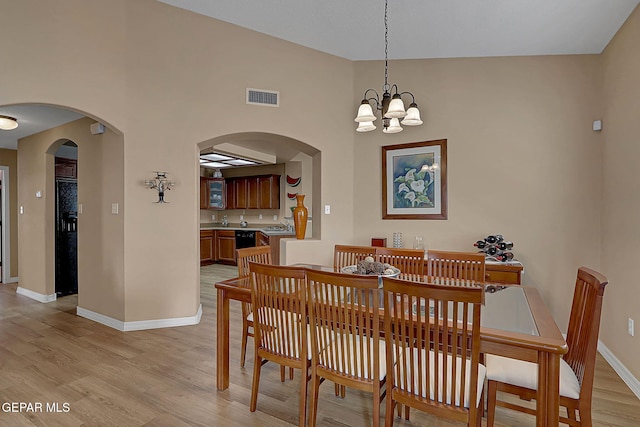 7101 Luz De Sol Dr, El Paso, TX 79912 - dining space featuring light wood-style floors, arched walkways, visible vents, baseboards, and a notable chandelier