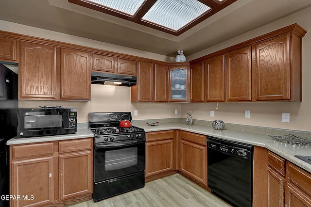 7101 Luz De Sol Dr, El Paso, TX 79912 - kitchen with light countertops, under cabinet range hood, light wood-type flooring, and black appliances