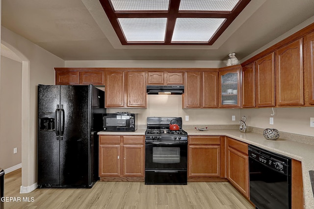 7101 Luz De Sol Dr, El Paso, TX 79912 - kitchen with under cabinet range hood, light wood finished floors, light countertops, and black appliances